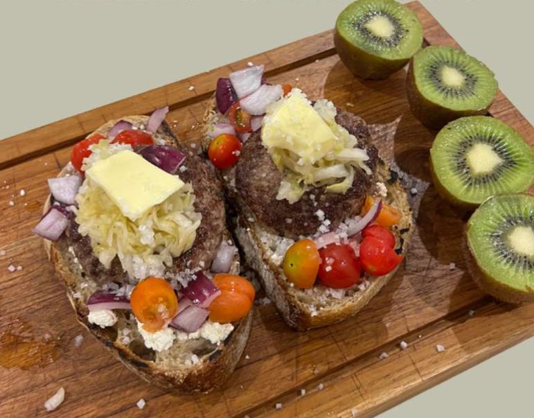 Tostas de pan de masa madre con hamburguesa, tomate cherry, cebolla morada y kiwi